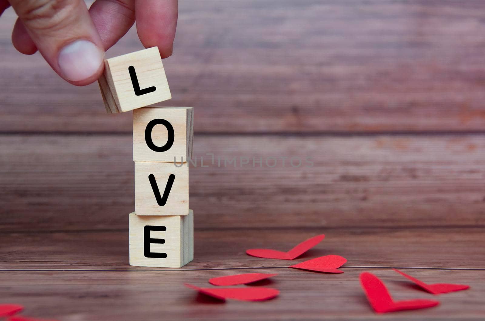 Love text on wooden blocks with heart shape and wooden background. Romance and relationship concept.
