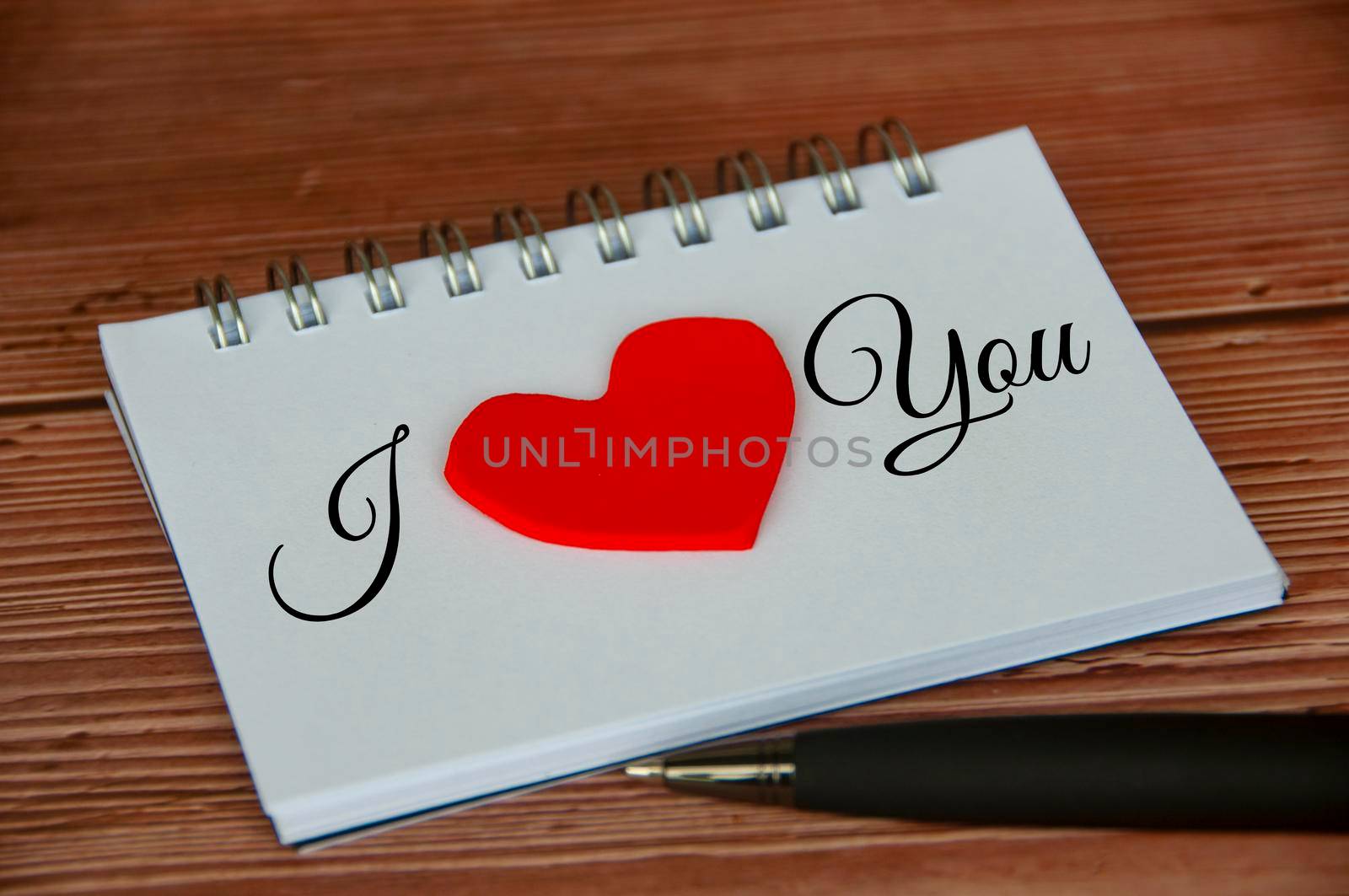 I love you text on notepad with wooden cover and pen background. Romance and relationship concept.