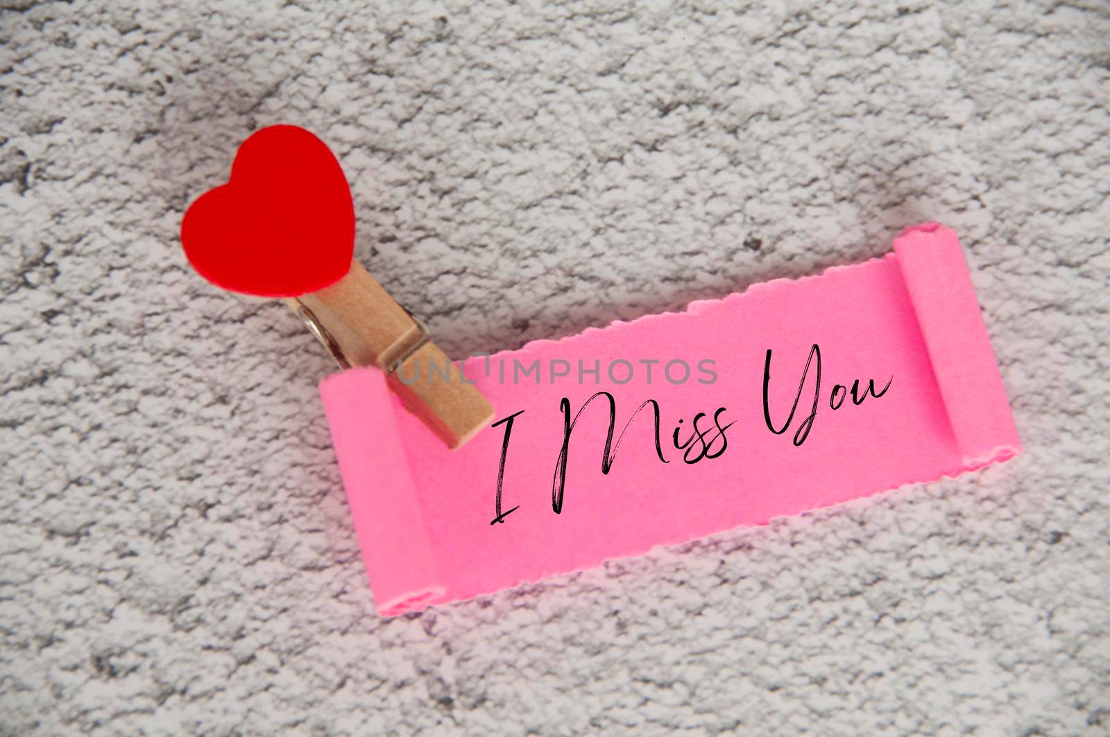 I miss you text on torn pink paper. Romance and relationship concept.
