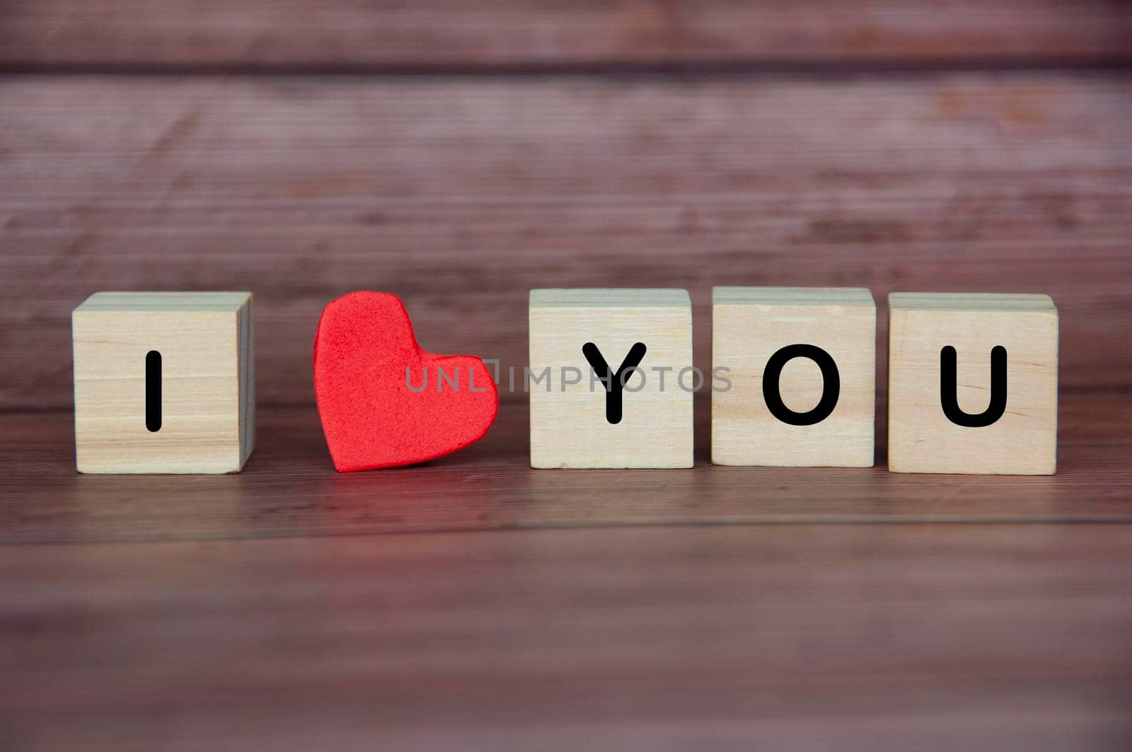 I love you text on wooden blocks with heart shape and wooden background. Romance and relationship concept.
