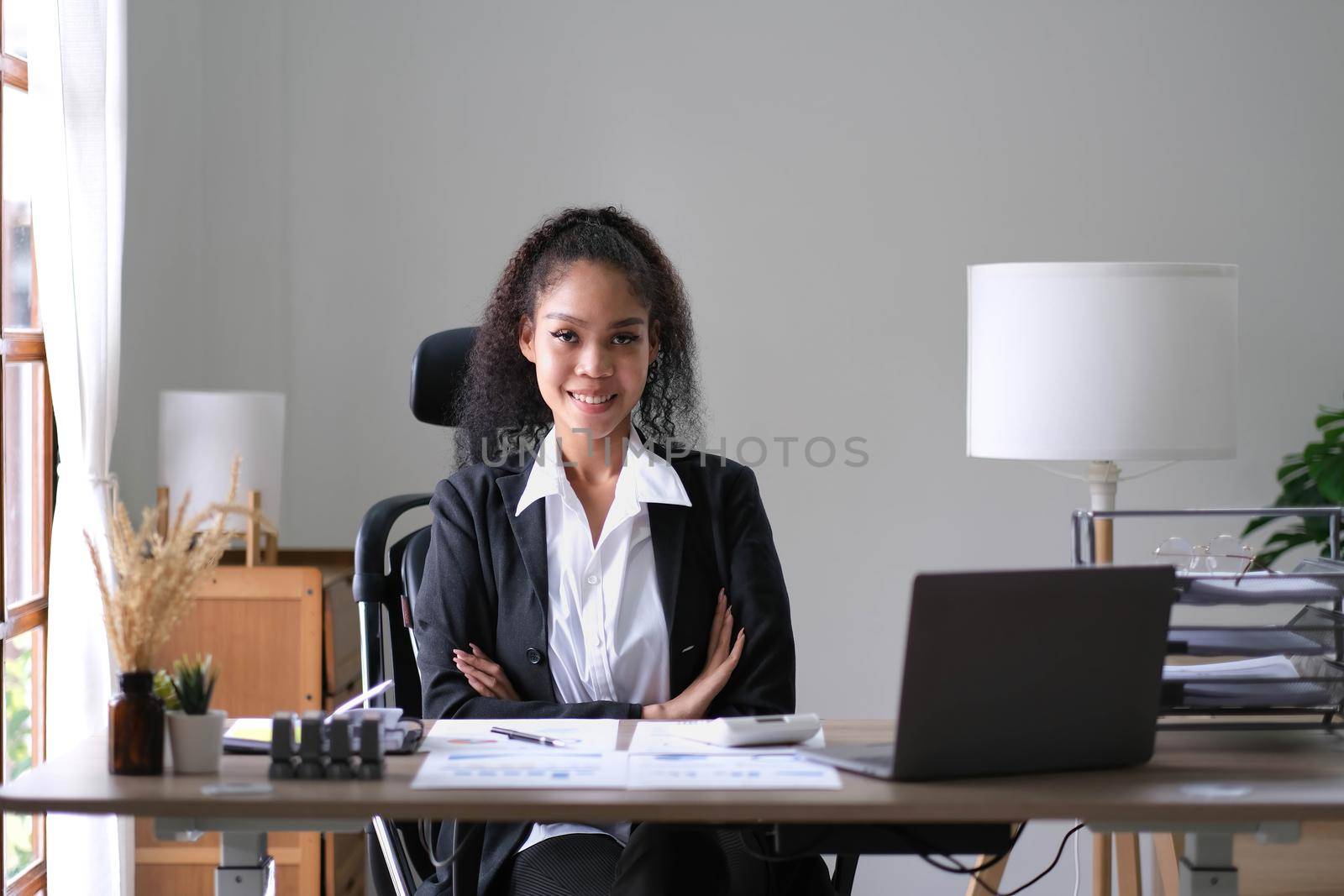 Smiling beautiful female professional manager standing with arms crossed looking at camera, happy confident business woman corporate leader boss ceo posing in office, headshot close up portrait by wichayada