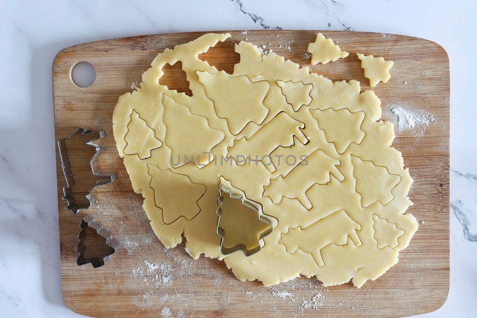 the process of cutting figures from shortcrust pastry for cookies with forms in the form of Christmas trees and animals