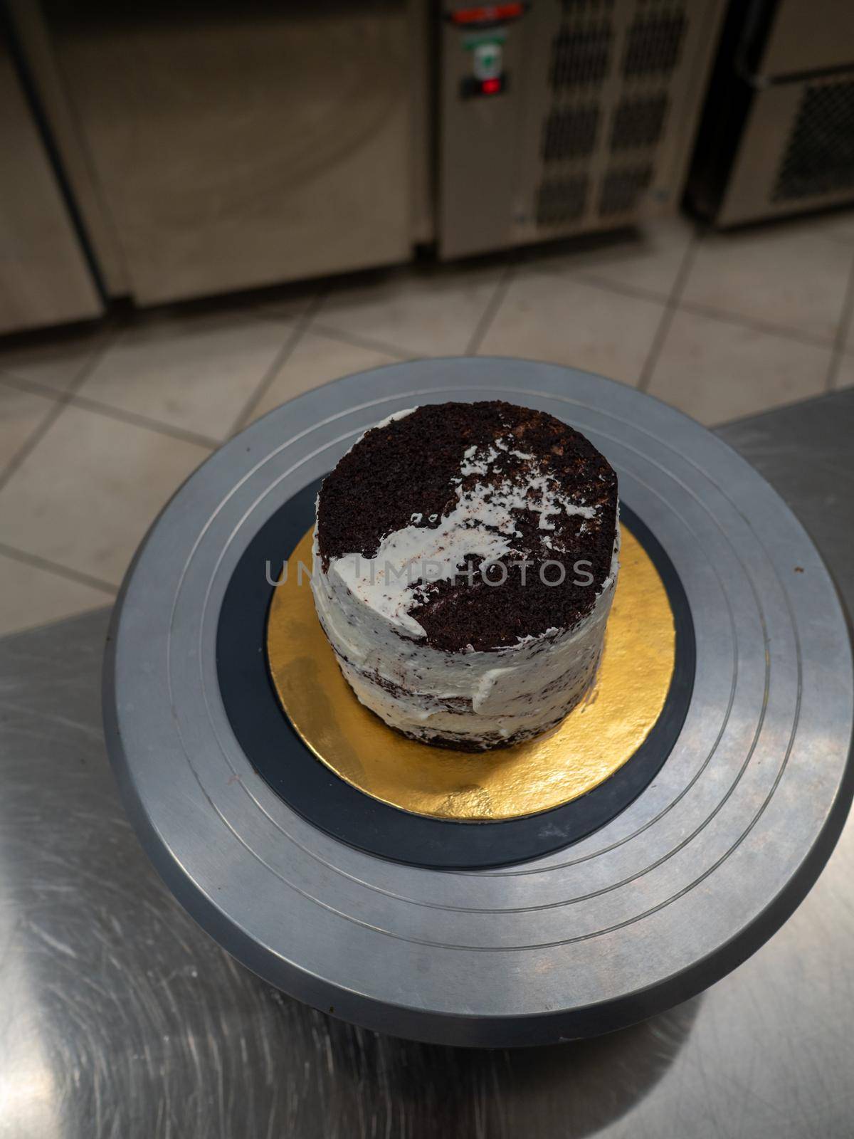 Decorator using spatula and scraper to smooth buttercream on a frosted cake