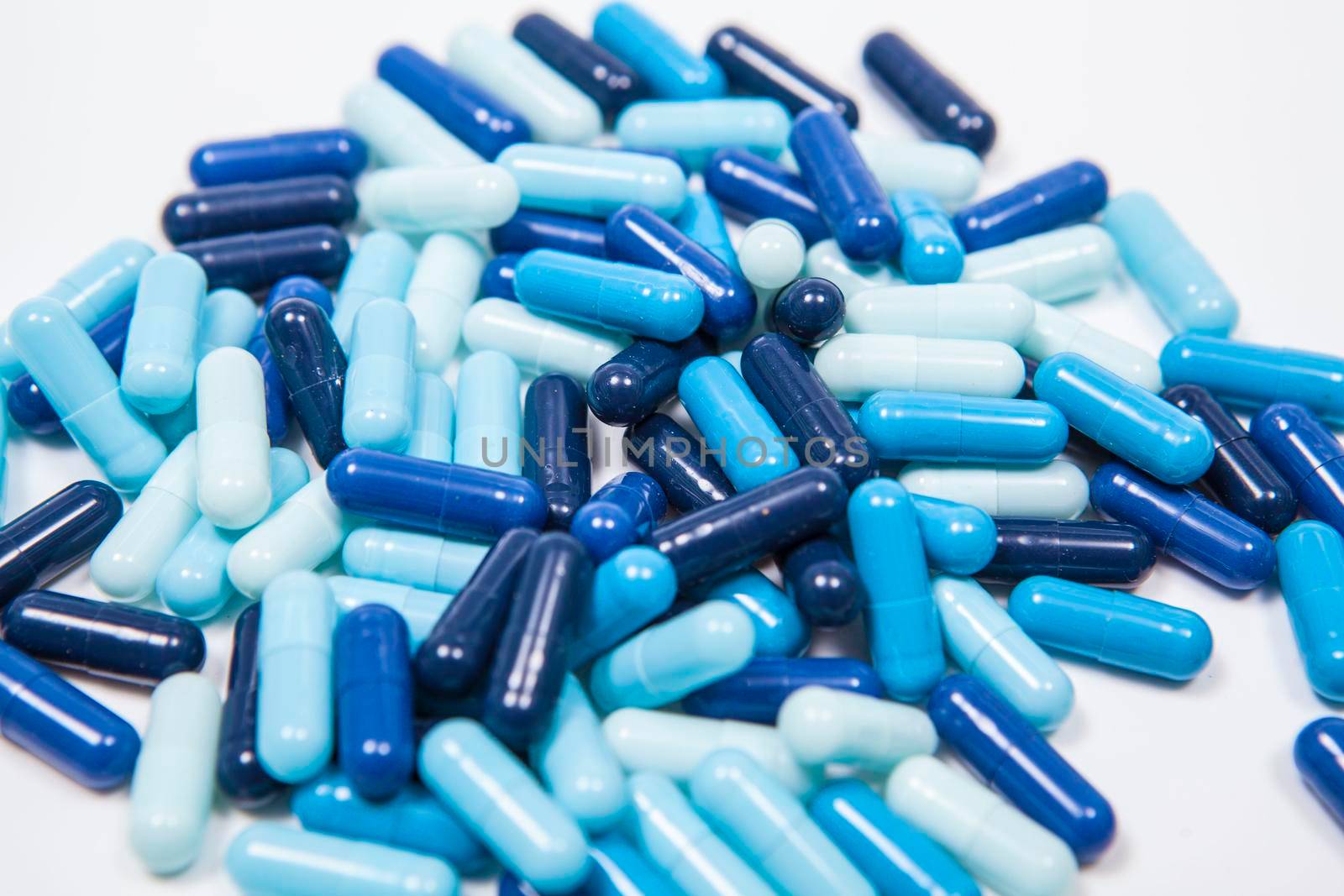 Pile of blue capsules isolated on white