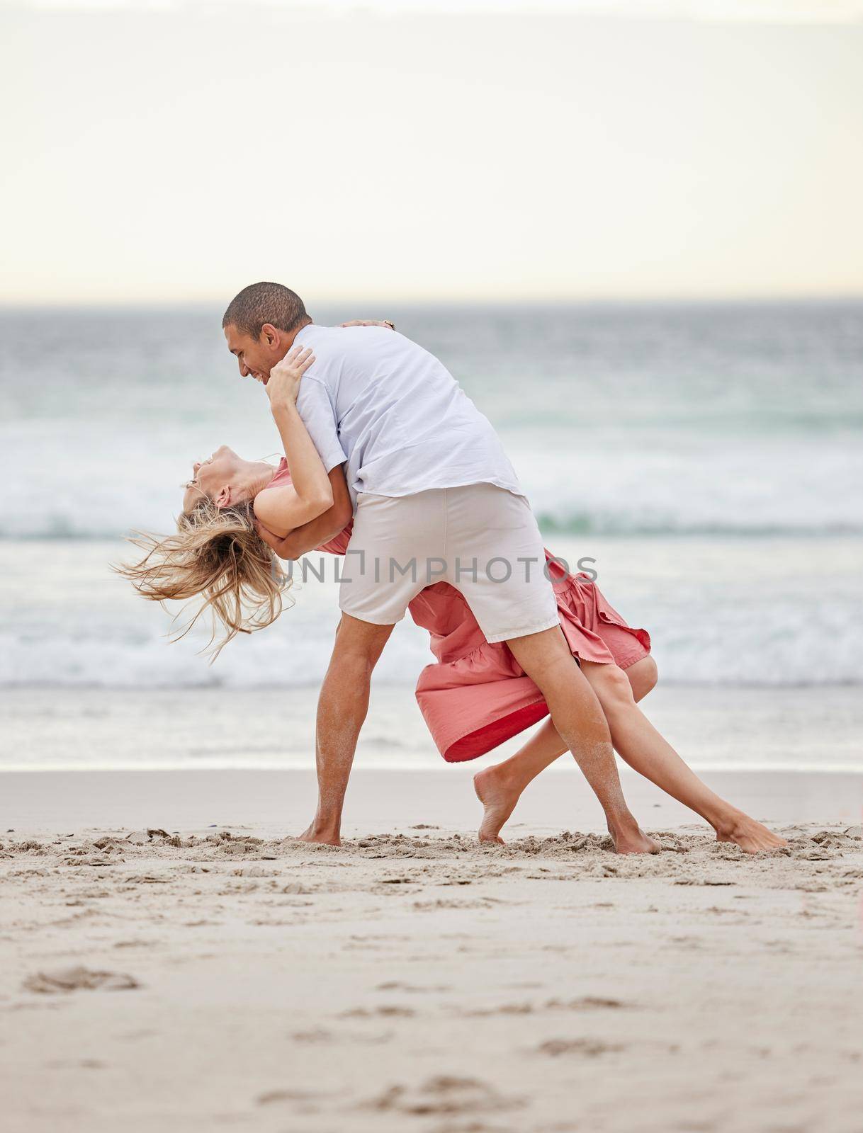 Dancing, happy couple and beach celebrate of love, trust and engagement on romantic luxury holiday travel Bali vacation. Man and woman or dancer couple celebration on sea water, sand and sunset ocean.