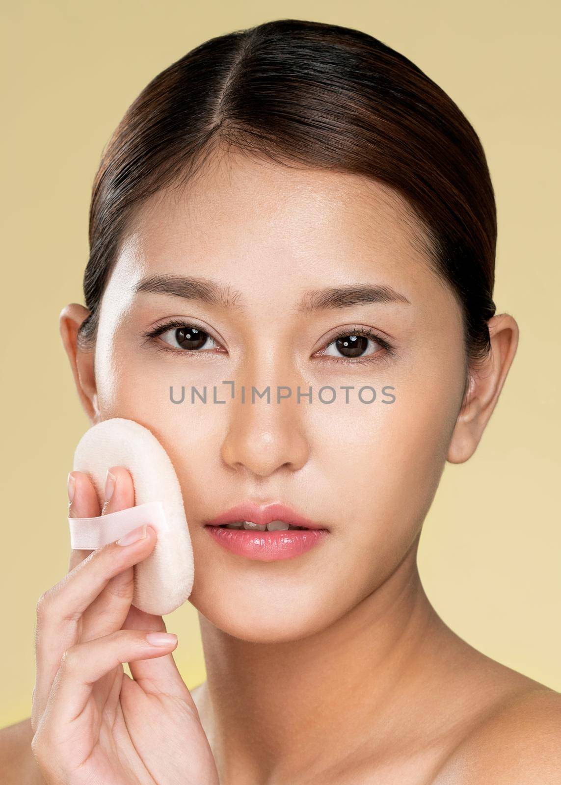 Closeup ardent woman applying her cheek with dry powder and looking at camera. Portrait of younger with perfect makeup and healthy skin concept.