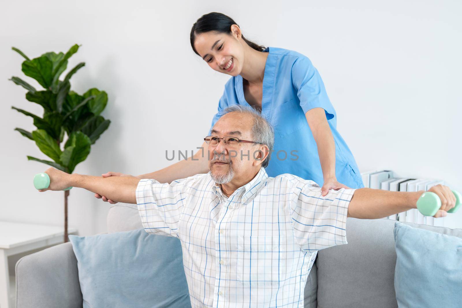 Contented senior patient doing physical therapy with the help of his caregiver. Senior physical therapy, physiotherapy treatment, nursing home for the elderly