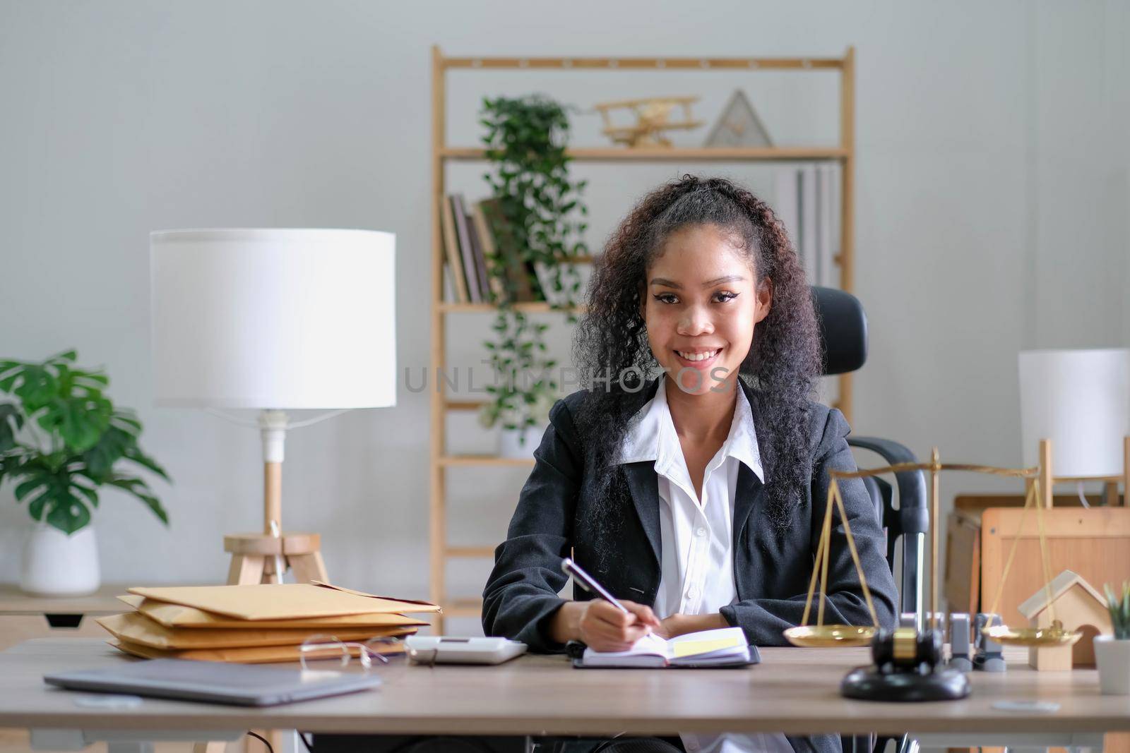 Portrait of young female Lawyer or attorney working in the office, smiling and looking at camera. by wichayada