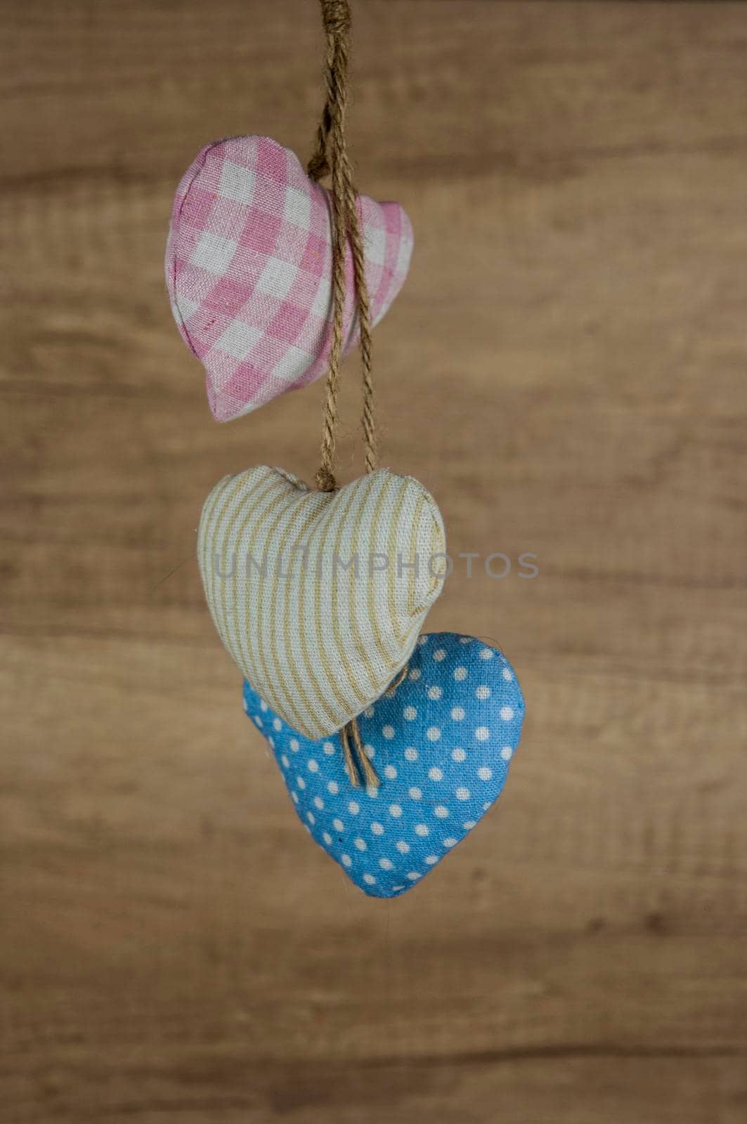 Fabric colorful hearts hanging on brown wooden wall. Happy Valentines Day