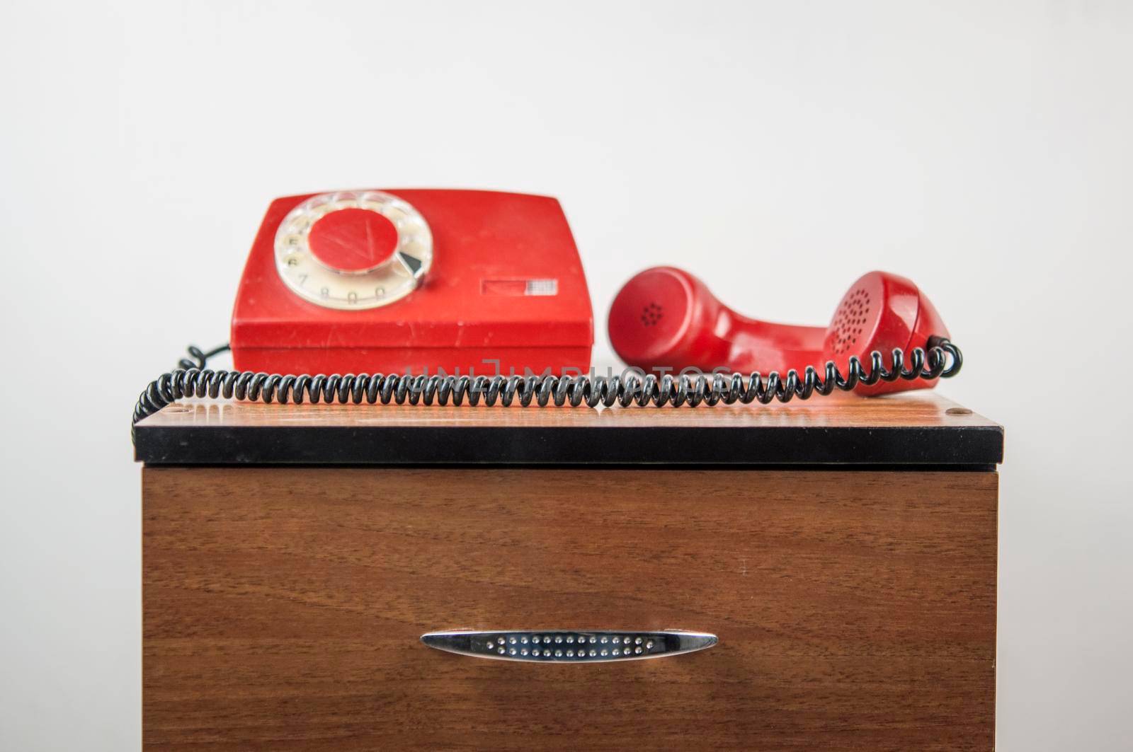 Retro rotary telephone on wooden table over white wall in room