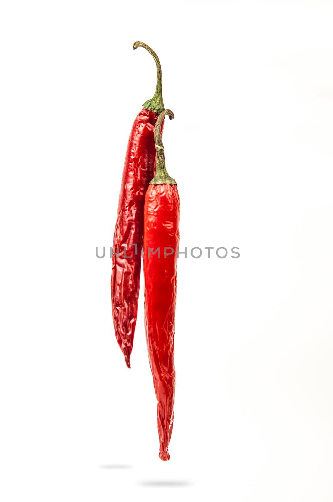 Falling red chili or chilli pepper on white background