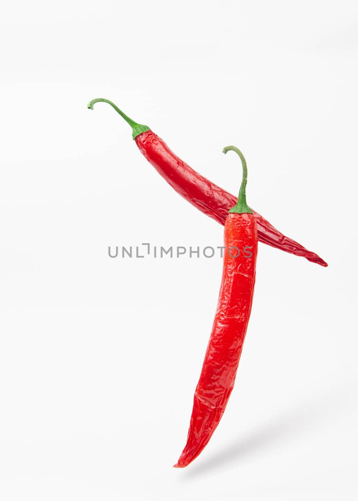 Falling red chili or chilli pepper on white background