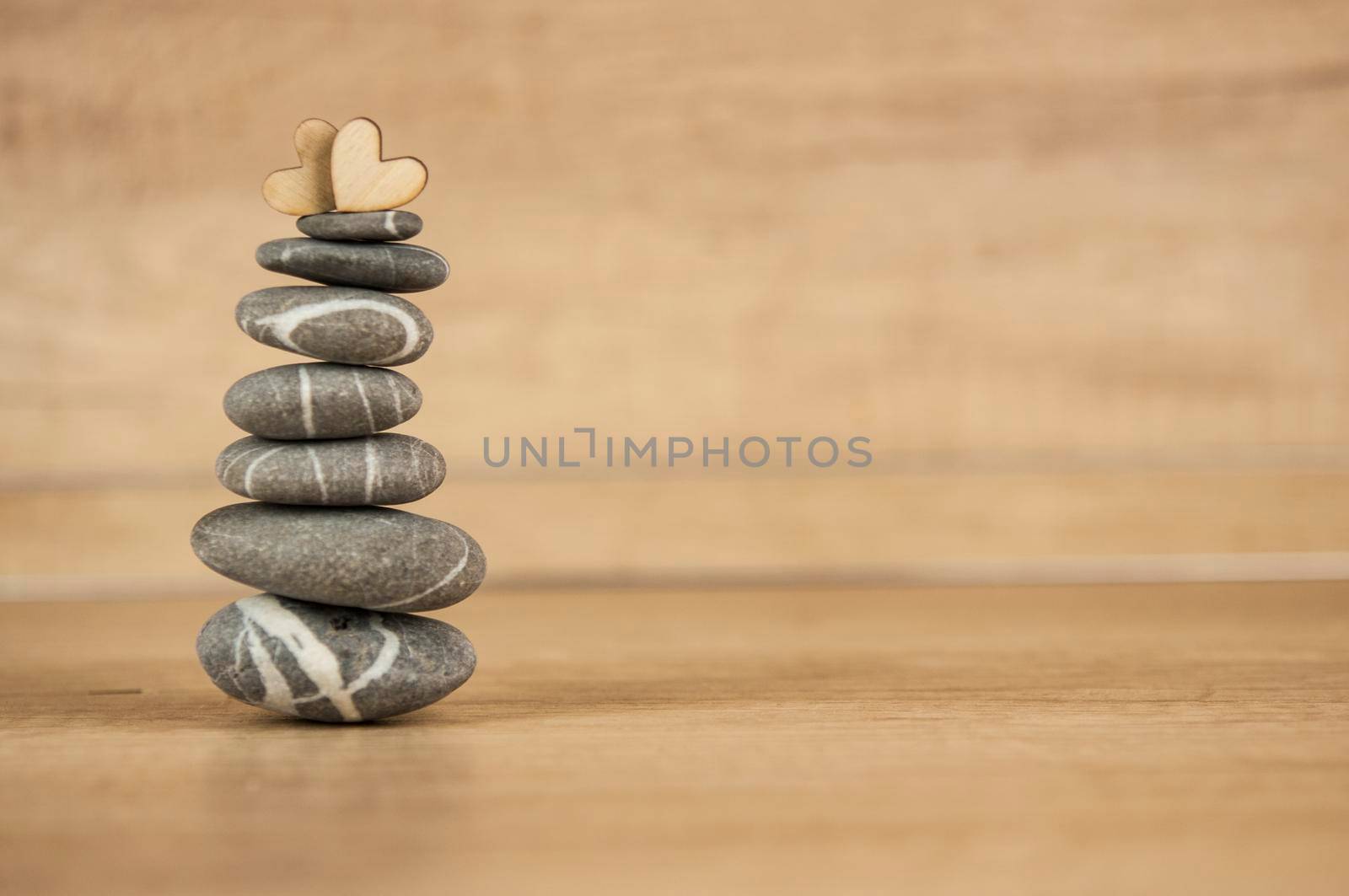 Stone cairn on wood background, simple poise stones, simplicity harmony and balance, rock zen sculptures by inxti