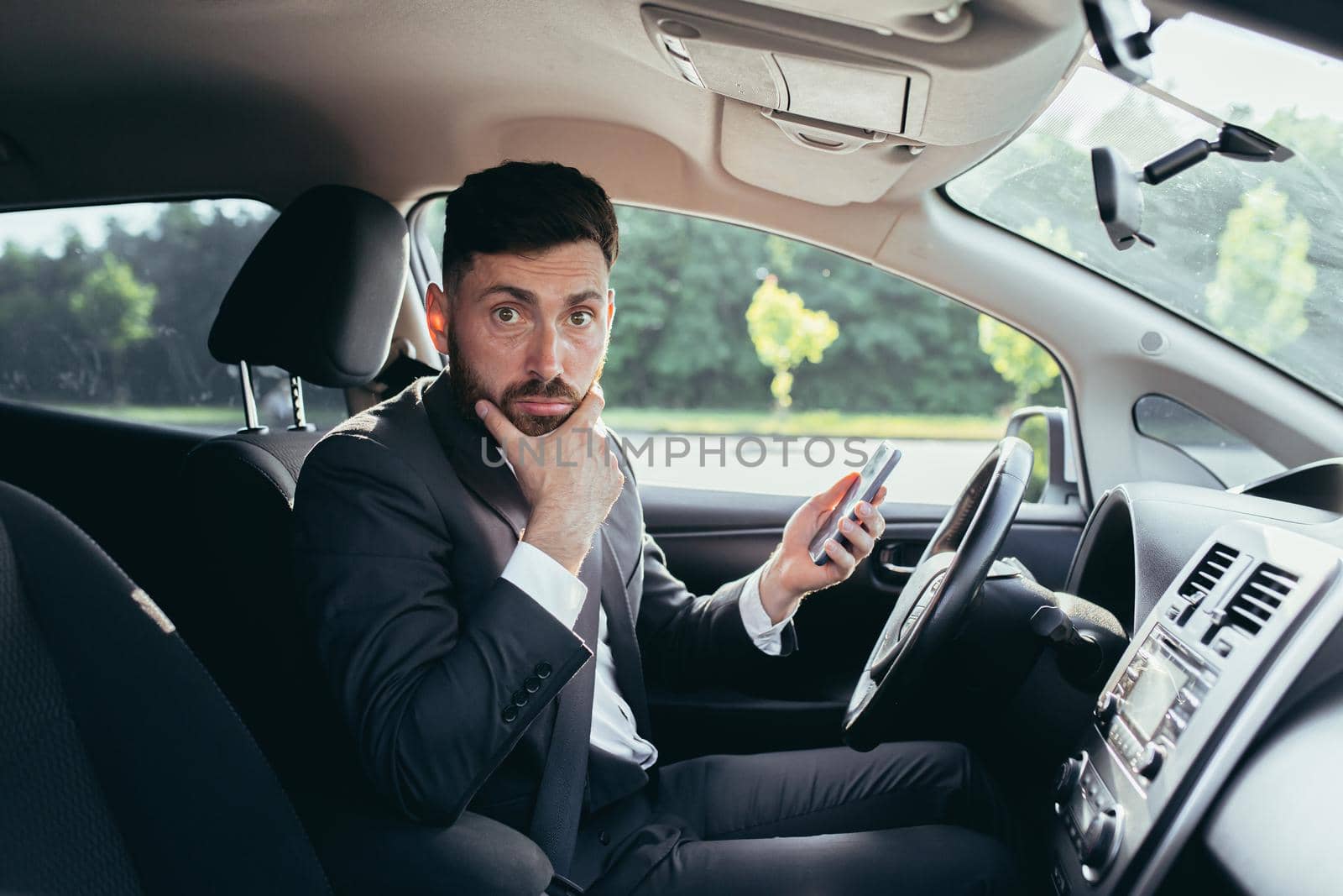 man sitting in the car, surprised reading the news from the phone by voronaman