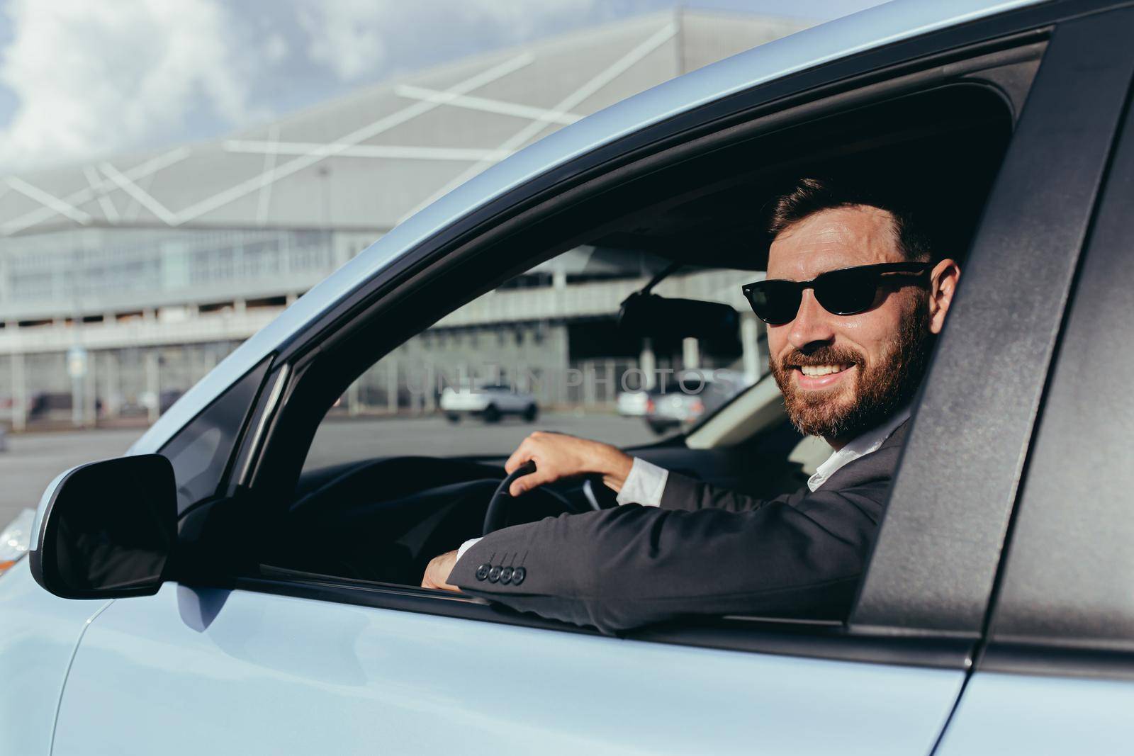 Businessman in black glasses sitting behind the wheel of a car