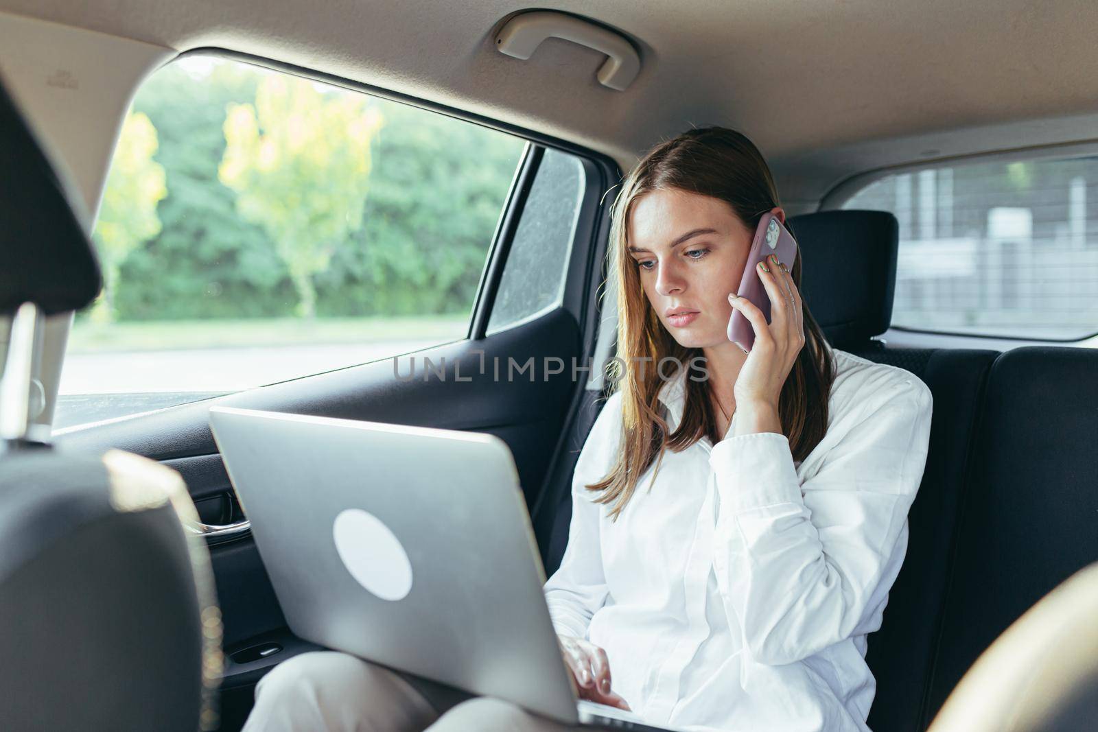 Woman sitting in the car and working with a laptop