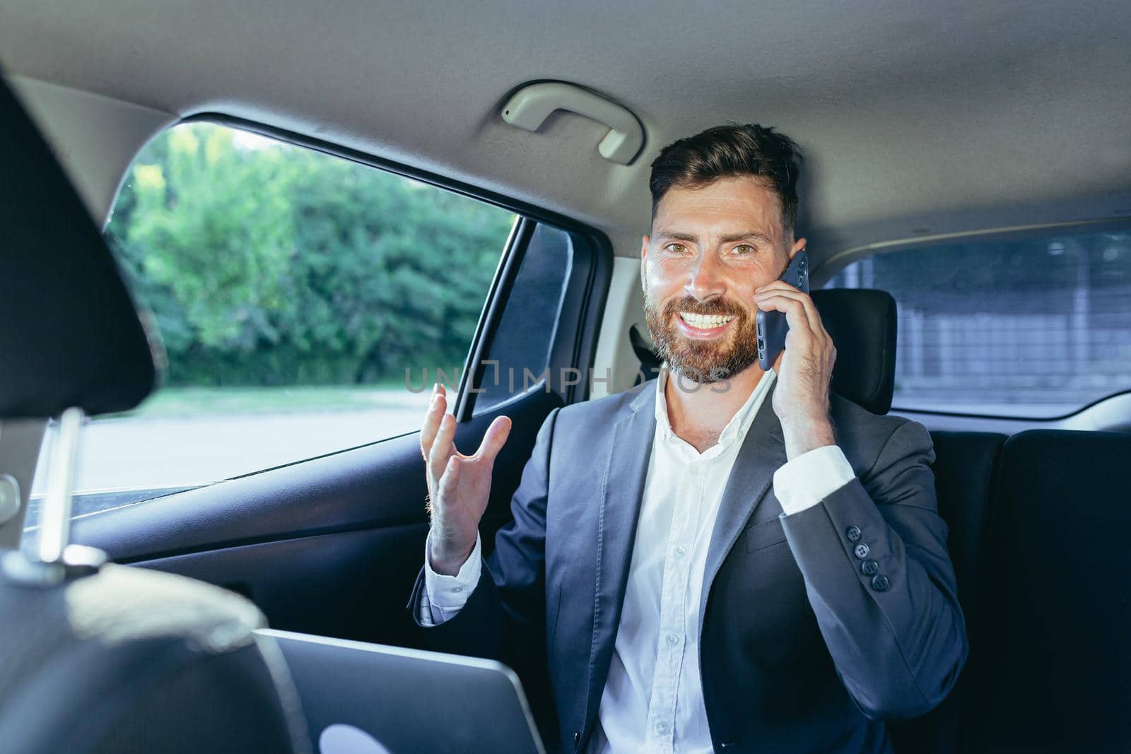 Close-up portrait of a man, a car passenger talking on the phone and looking out the open window