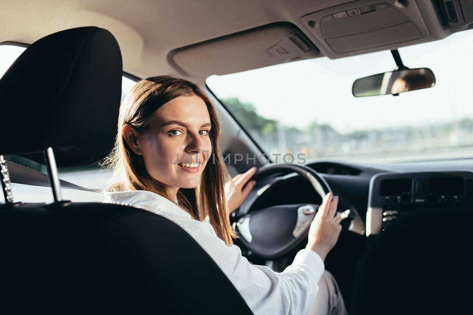 Portrait of a successful woman driving a car, smiling rejoicing and looking at the camera