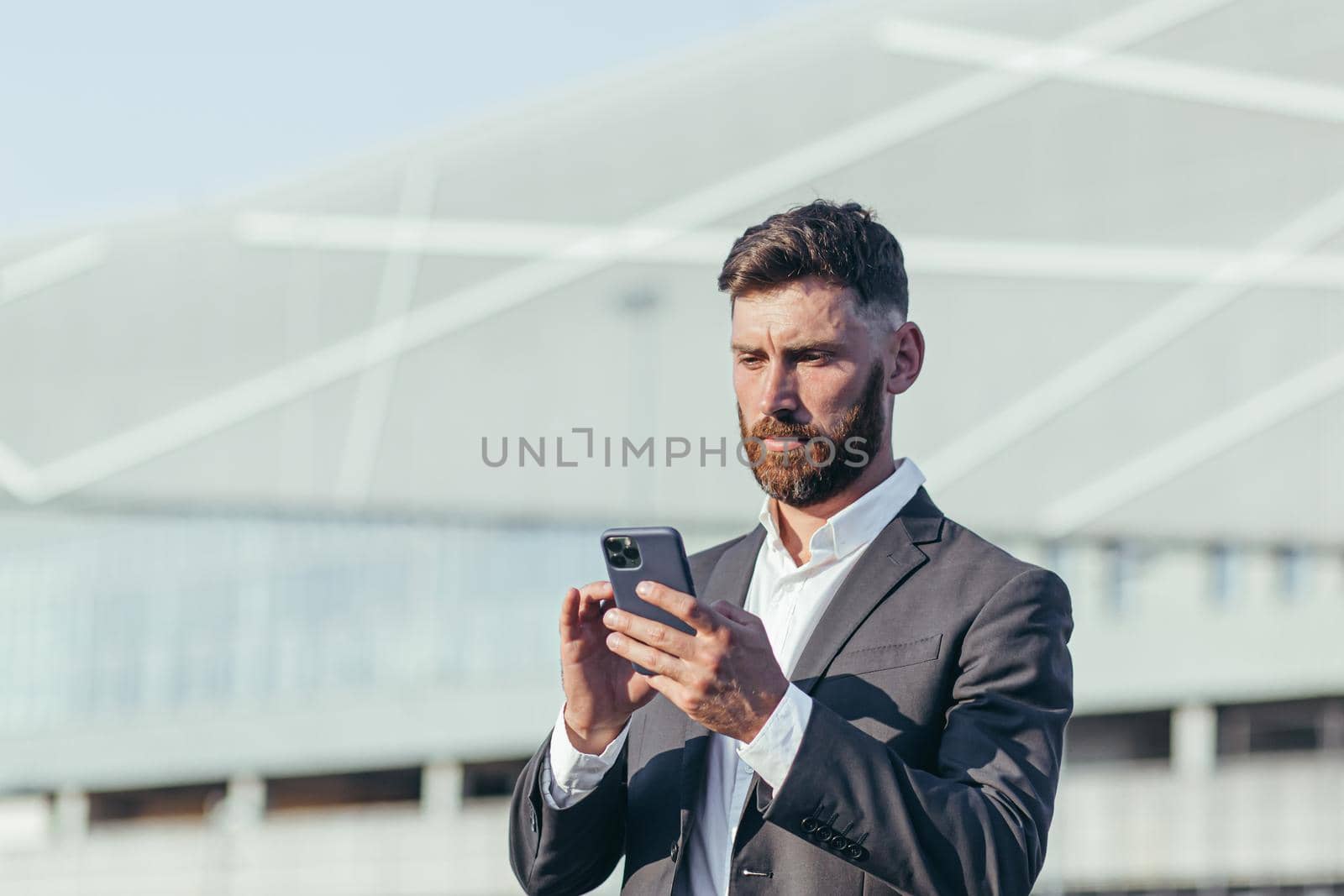 Businessman on the background of the office center is corresponding in a mobile phone