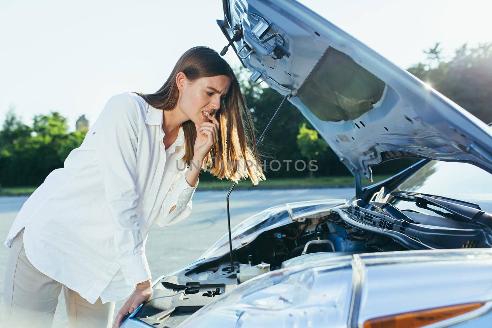 Confused woman examines the car engine