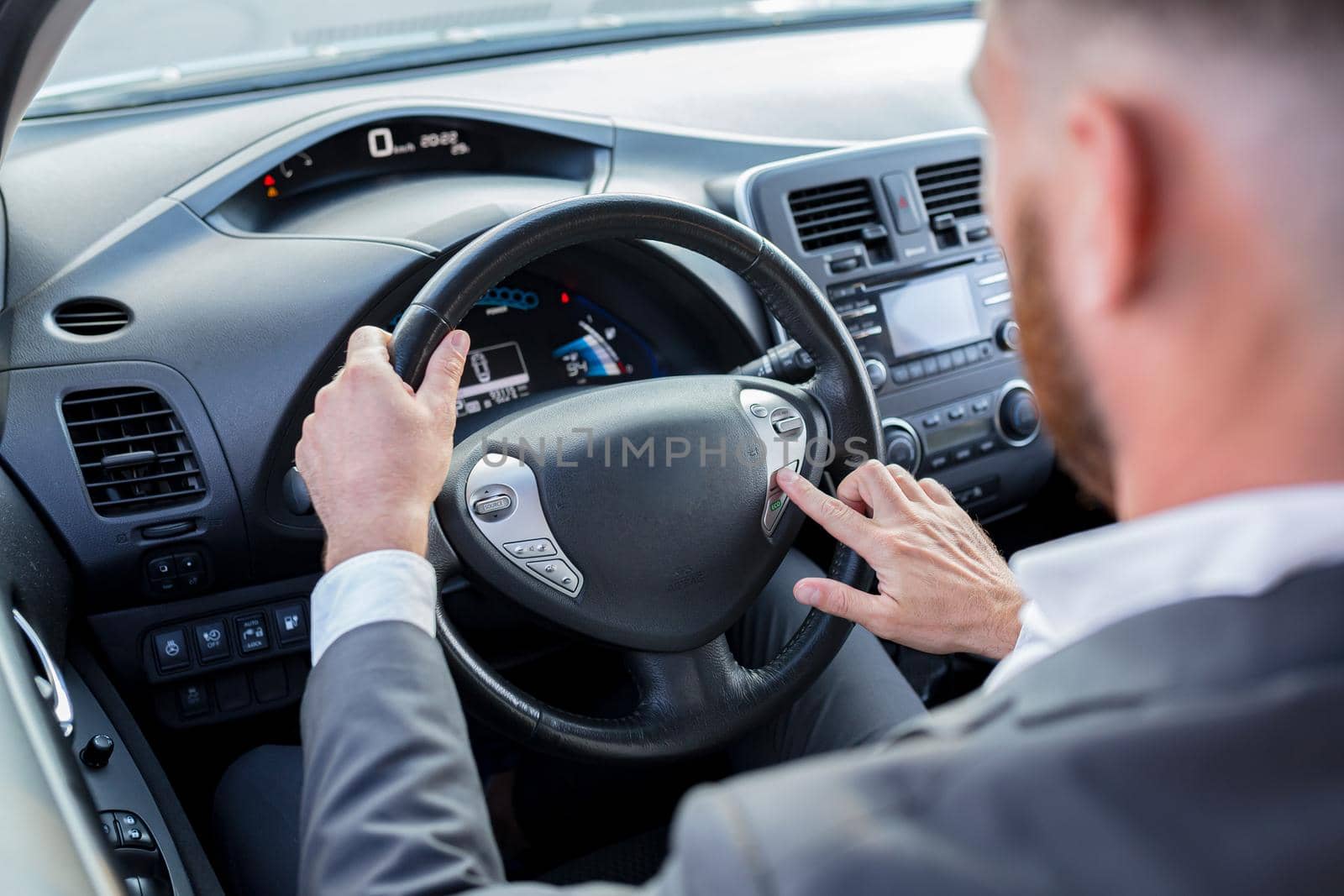 Close-up photo of man's hand switching car mode on steering wheel buttons