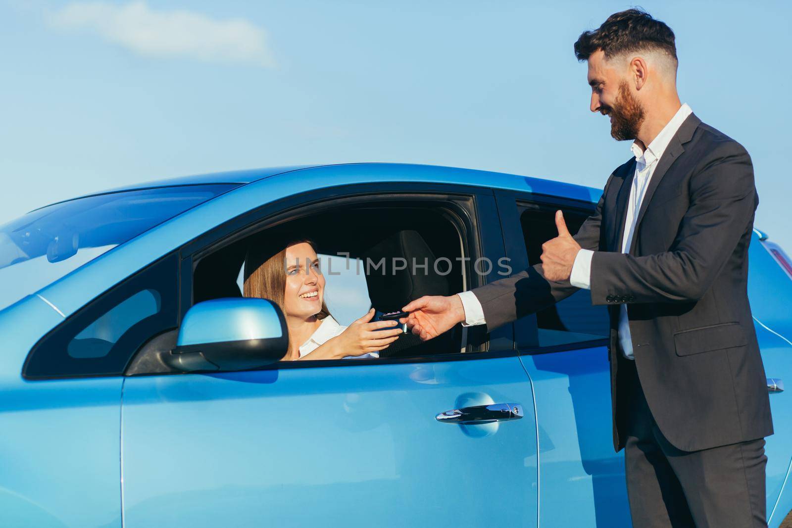 a man hands over the car keys to a woman sitting in the car