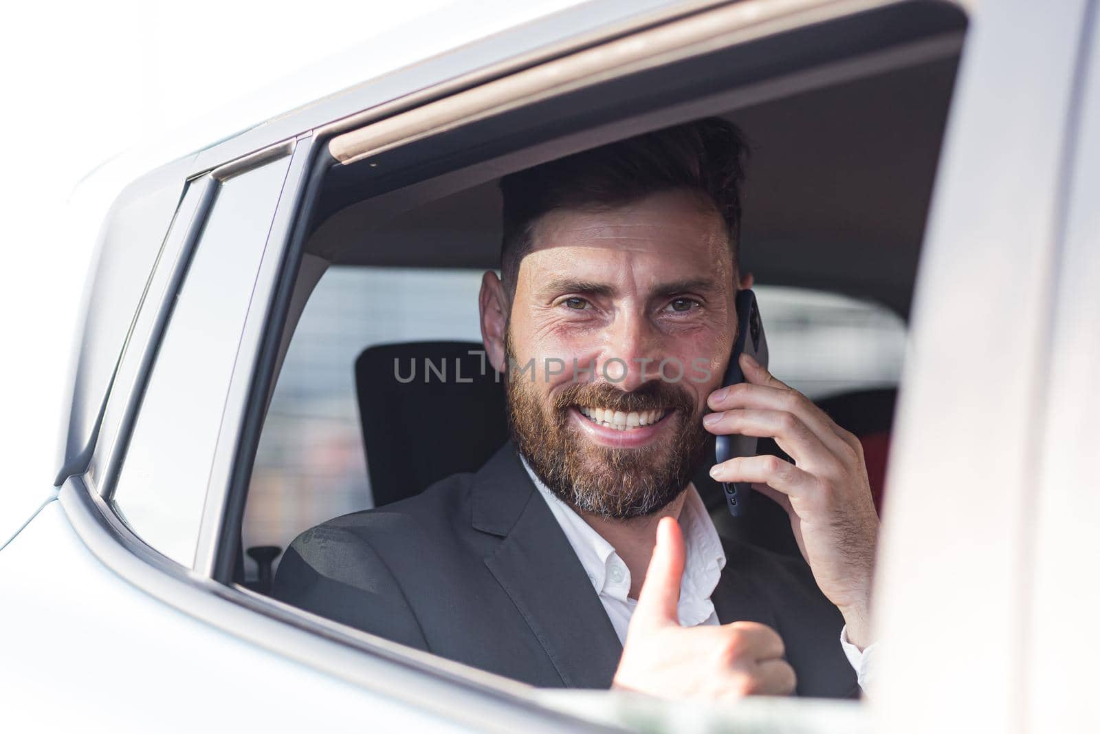 Close-up portrait of a man, a car passenger talking on the phone and looking out the open window