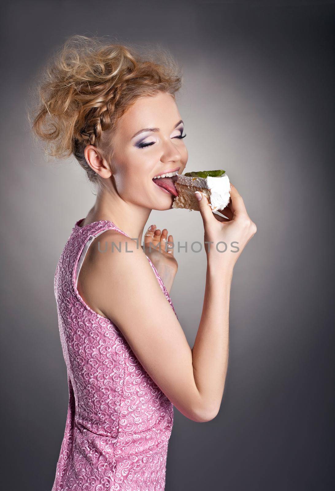 Pretty blonde woman eat sweet cake from fingers