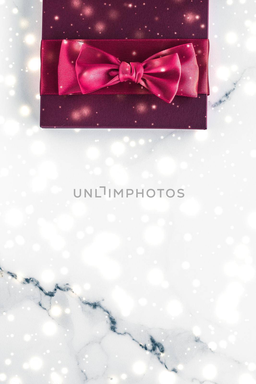 Winter holiday gifts with cherry silk bow and glowing snow on frozen marble background, Christmas presents surprise by Anneleven