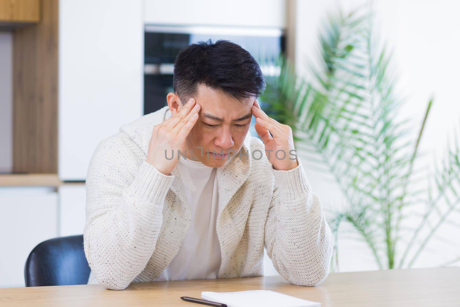 Thoughtful serious young asian man looking away. student writer sit at home office desk with laptop thinking of inspiration search solution ideas lost in thoughts dreaming solving financial problems