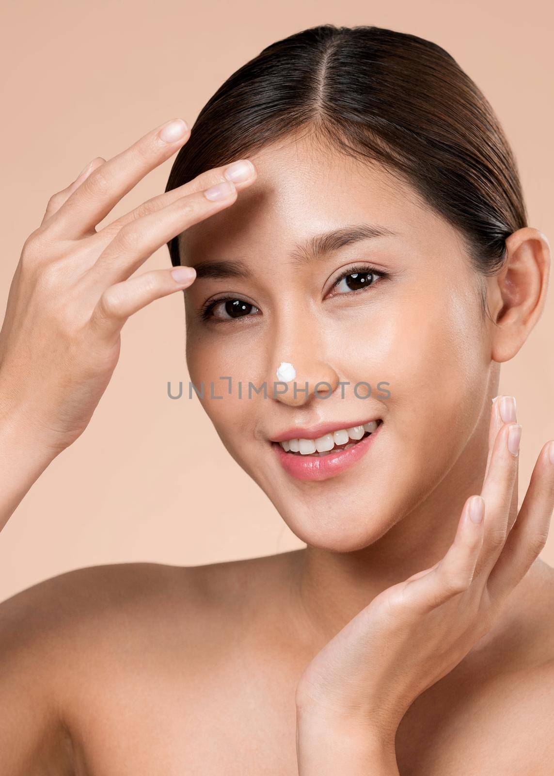 Closeup ardent girl with soft makeup applying moisturizing skincare cream on her face, isolated background. Skincare cream applied by female model concept.