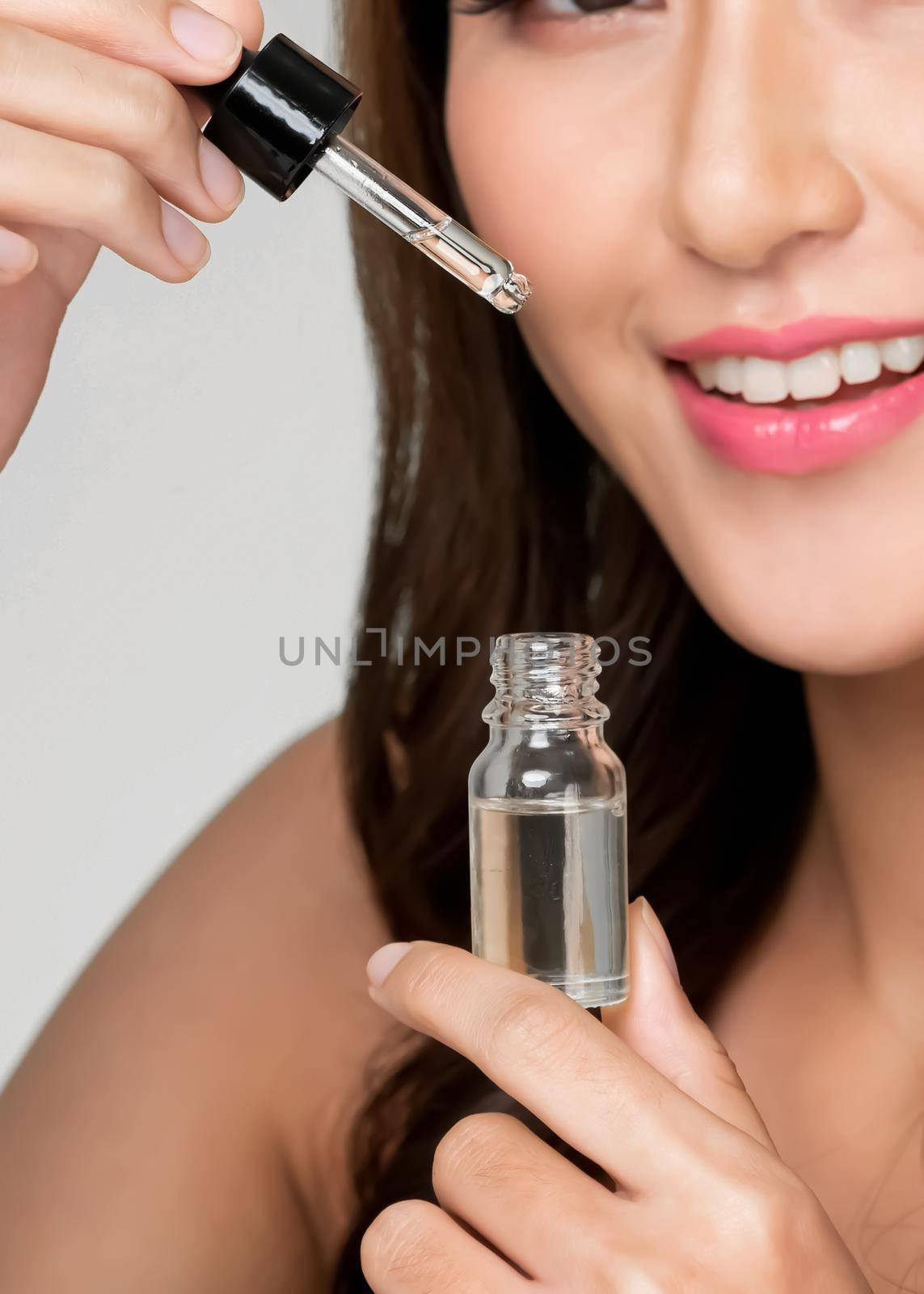 Closeup portrait of young ardent woman with healthy fresh skin taking cbd oil and dropper. Combination of beauty and cannabis for healthy skincare concept.