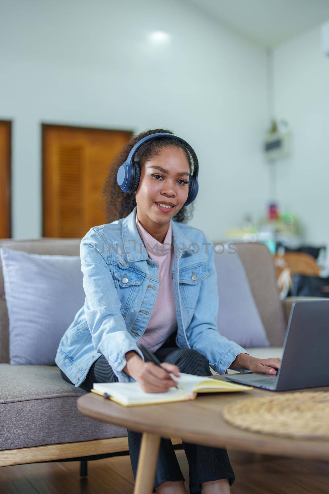African American using a notebook and computer to study online at home by Manastrong