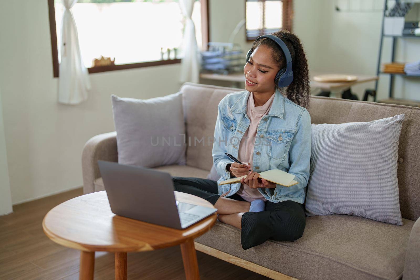 African American using a notebook and computer to study online at home by Manastrong