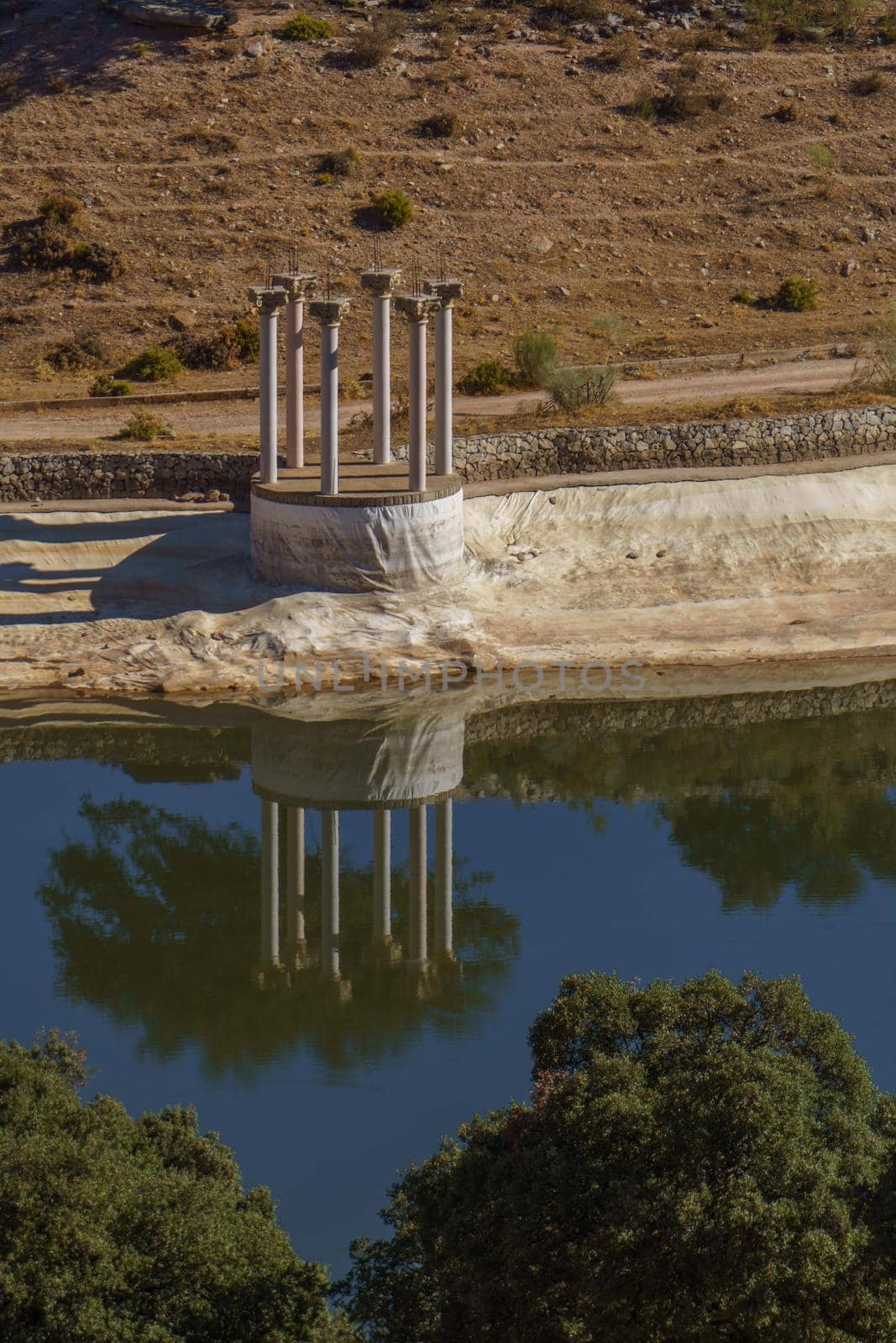 set of columns reflected in a mountain landscape lake
