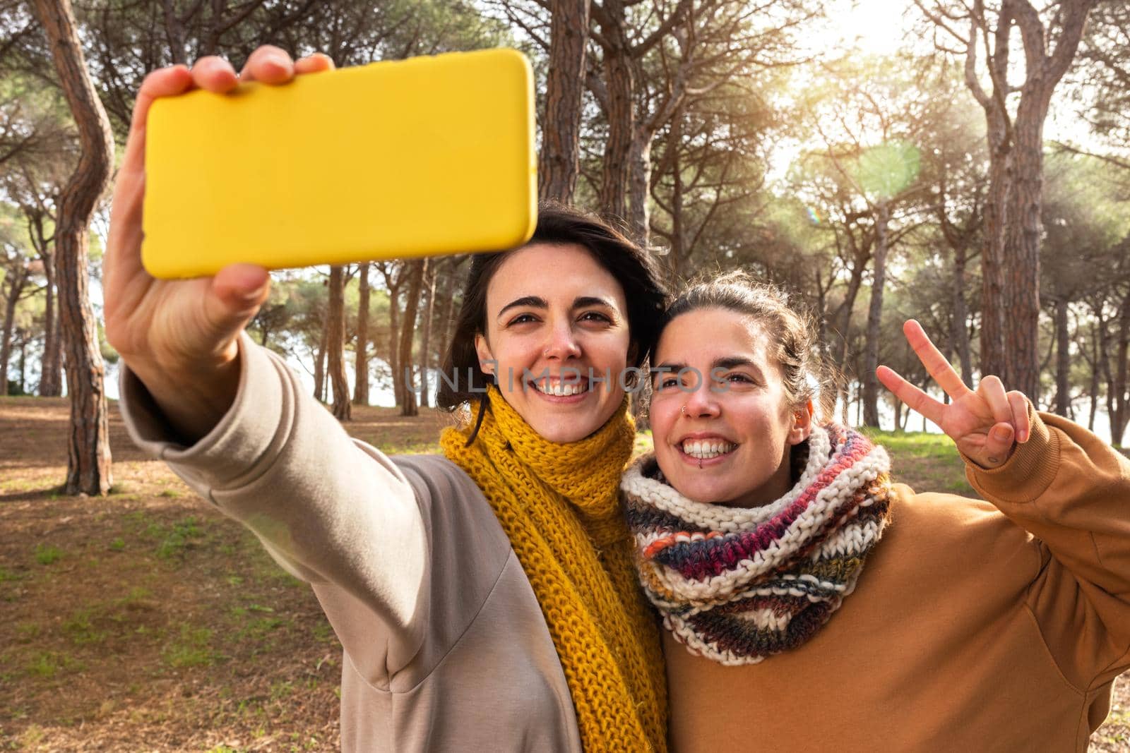 Happy young women take selfie using mobile phone during a walk in the forest. Social media and nature concept.