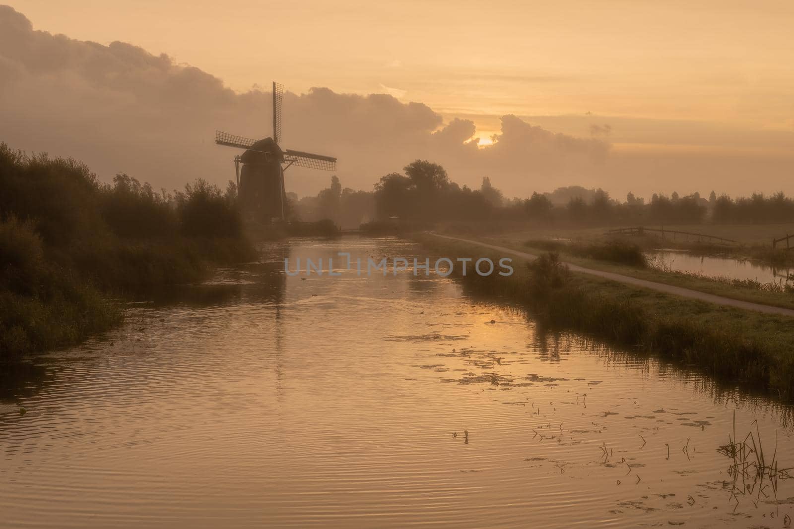 Calm and foggy golden sunrise morning on the Hazerswouder-Dorp windmill, Rietveldse, Netherlands. by ankorlight