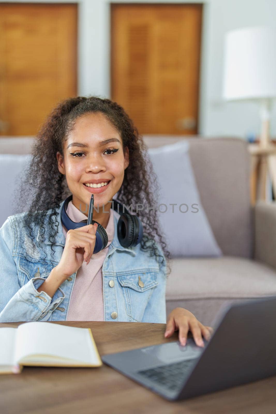 African American using a notebook and computer to study online at home by Manastrong