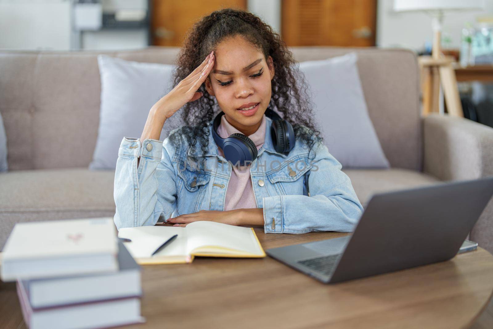 Portrait of an African American using computers and notebooks online and showing stressed faces and gestures in lessons learned