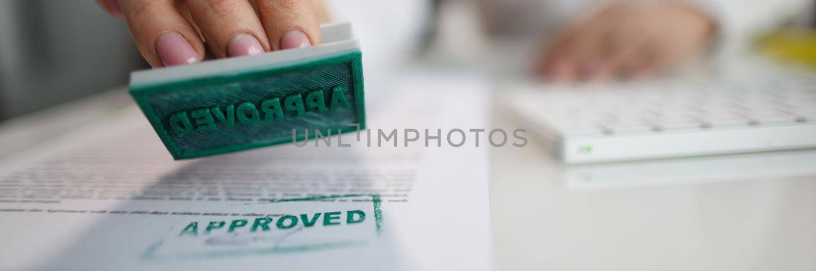 Manager hand putting stamp approved on document in office closeup. Authentication of papers concept