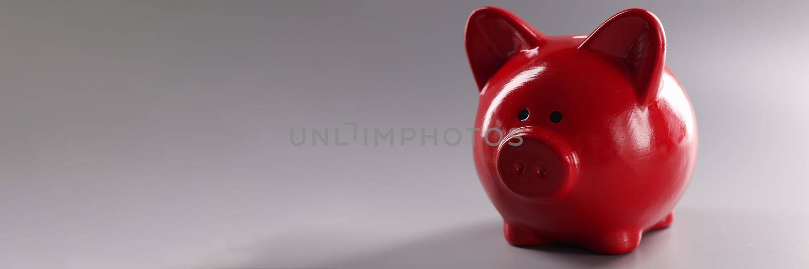 Closeup of red piggy banks for coins on gray background. Cash savings concept