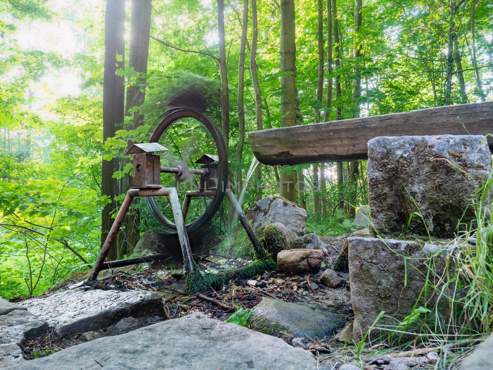 Water falling from the hollowed-out trough turns the mill wheel. Drinking water from a mountain spring