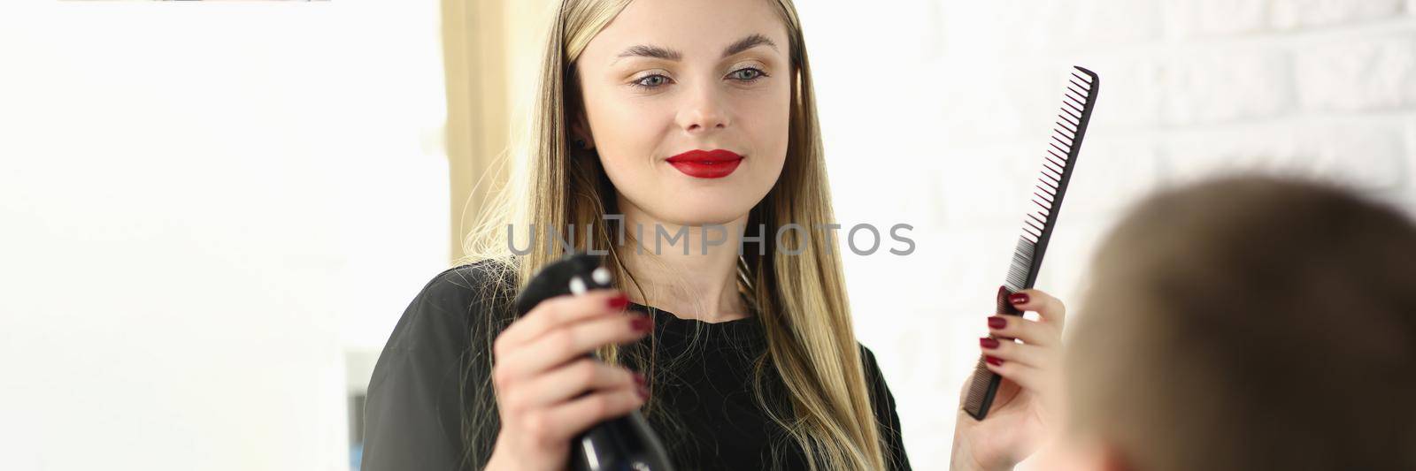 Hairdresser holding comb and spray with water in front of male client in beauty salon by kuprevich