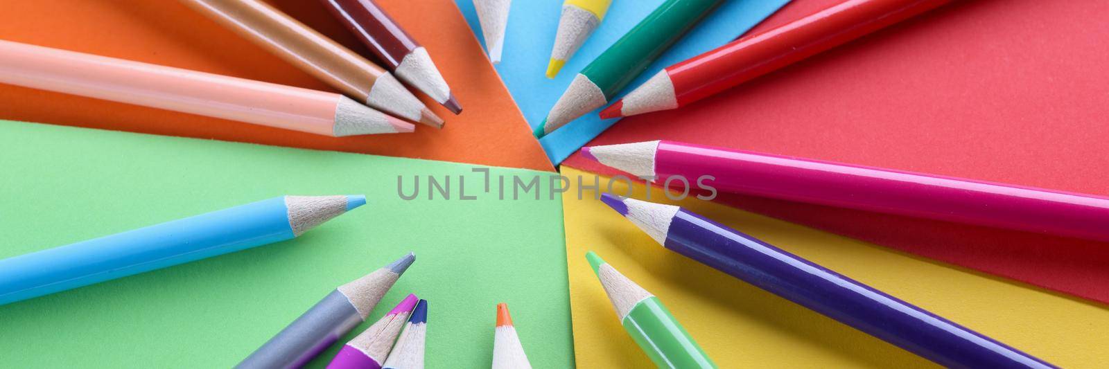 Lot of sharp wooden pencils lying on multicolored background closeup. Art class at school concept