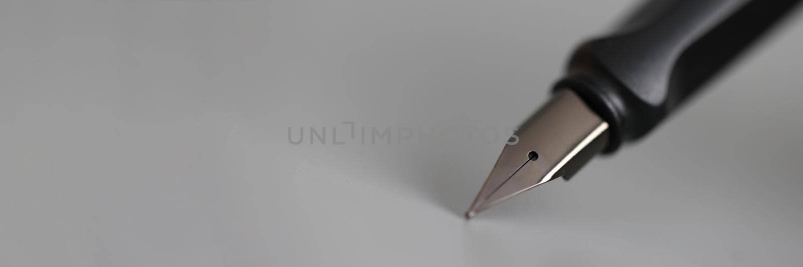 Closeup of metal ink pen head on gray background. Signing of documents concept
