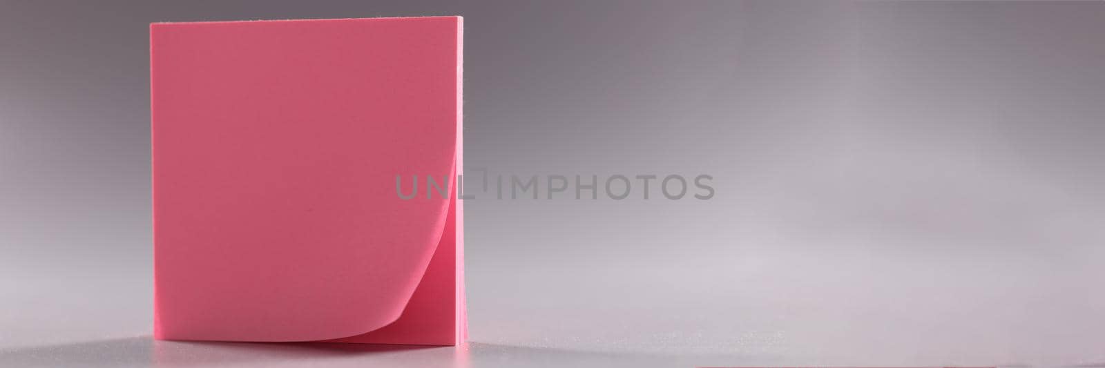 Closeup of block of pink note paper on gray background by kuprevich