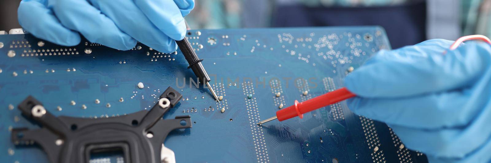 Repairman diagnosing breakdown in computer motherboard using tester closeup. Repair and maintenance of computer equipment and electronics concept