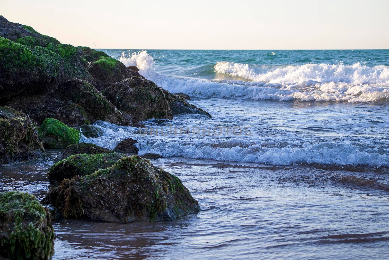 View of a waves on the beach and rocky shore. Shot taken in Ras Al Khaimah emirate. UAE. by pazemin