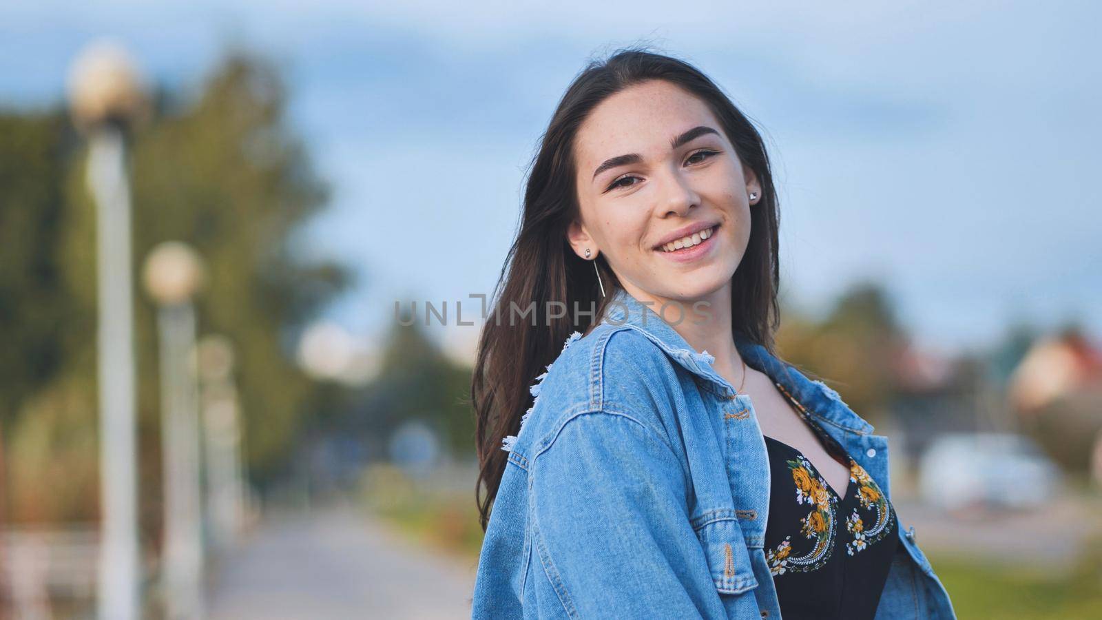 Portrait of a cheerful girl in a denim jacket at night in the city