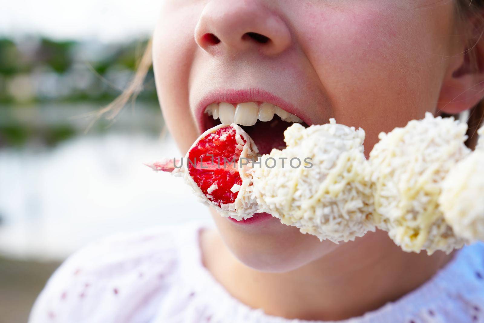 Beautiful girl eating a fresh red strawberry in white chocolate. strawberry white chocolate glaze